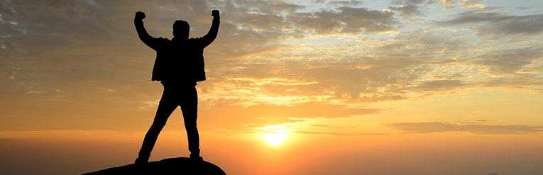 Man at the top of mountain as the sun sets  