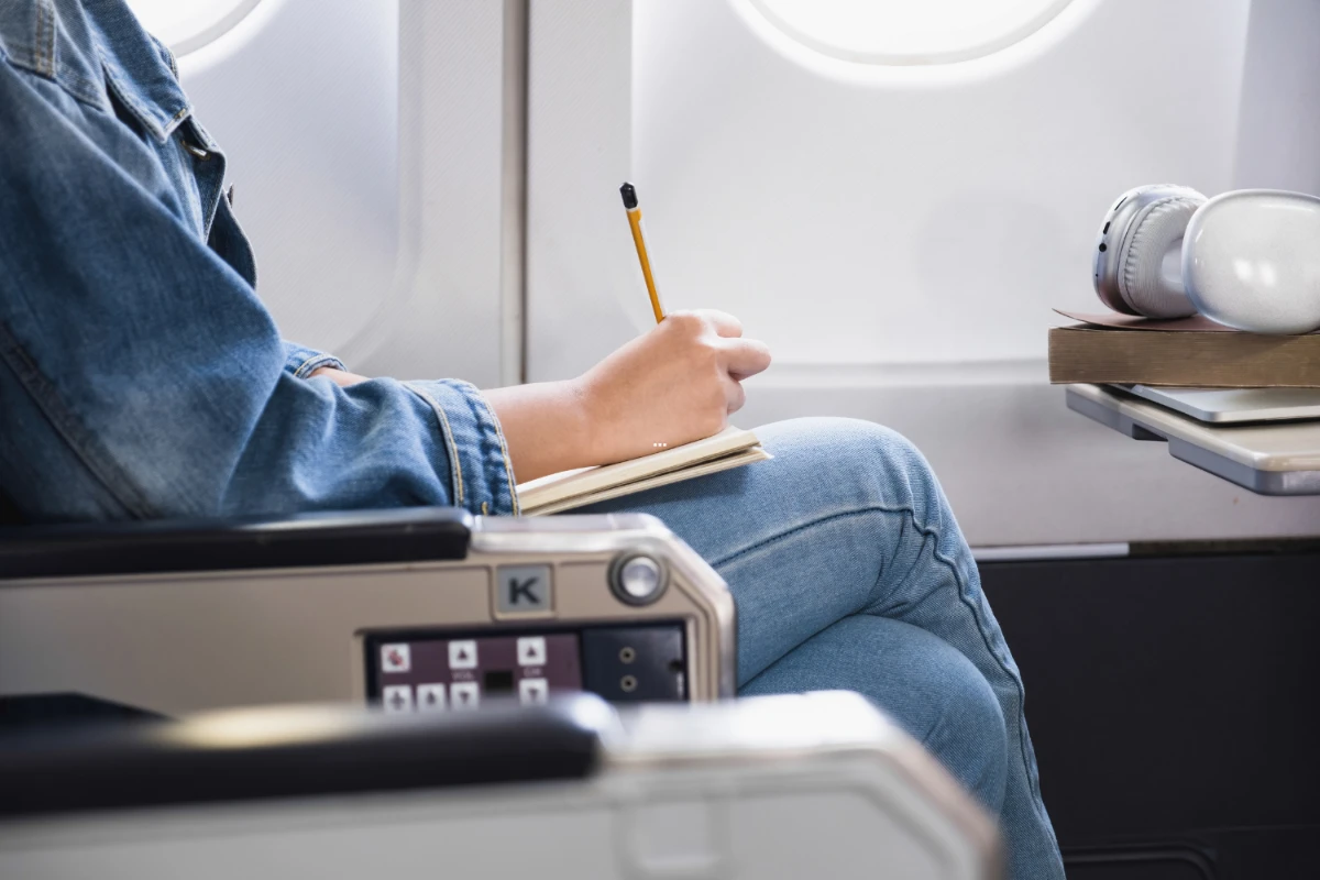 person filling out forms on airplane