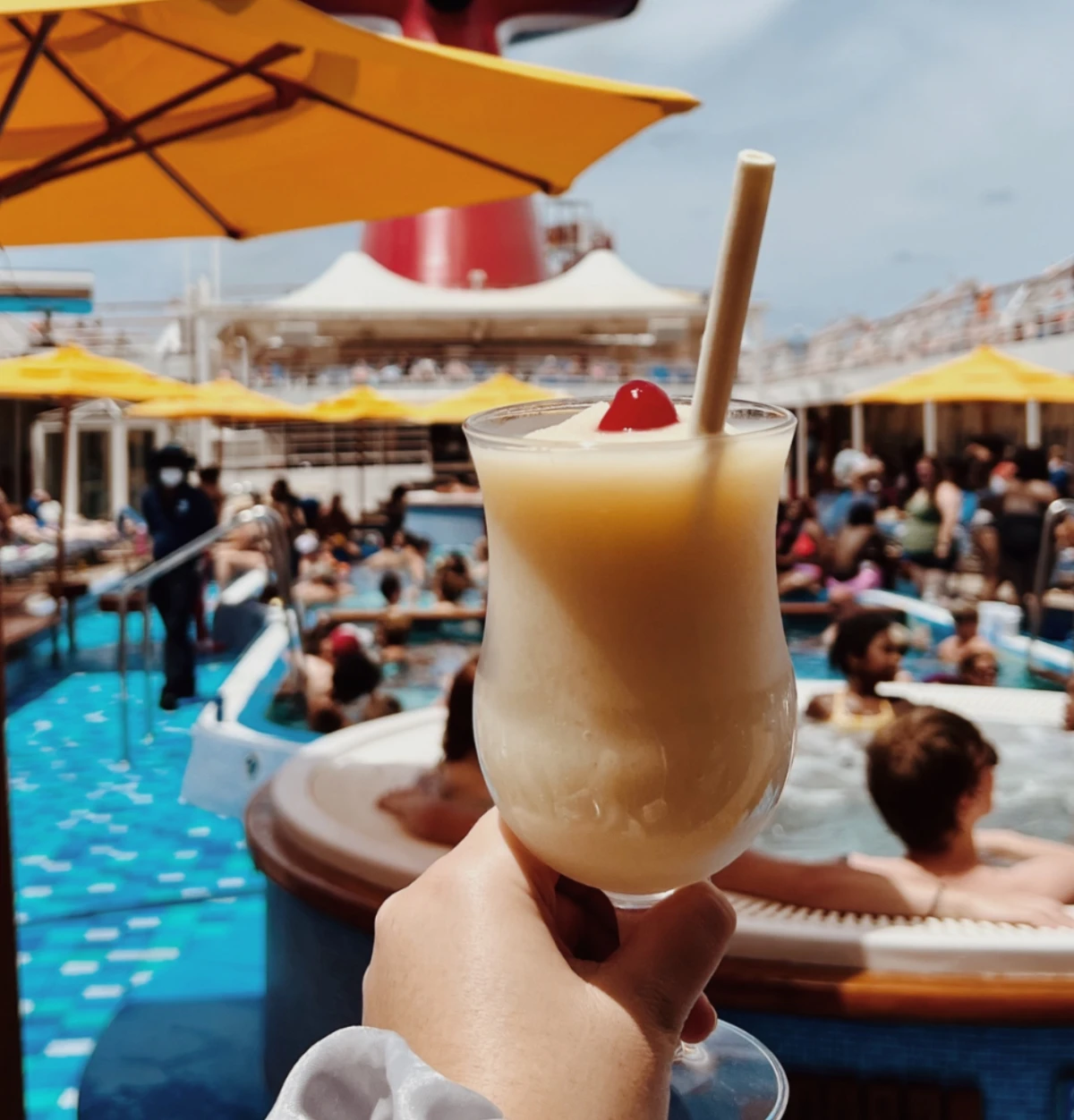 person holding drink on cruise deck